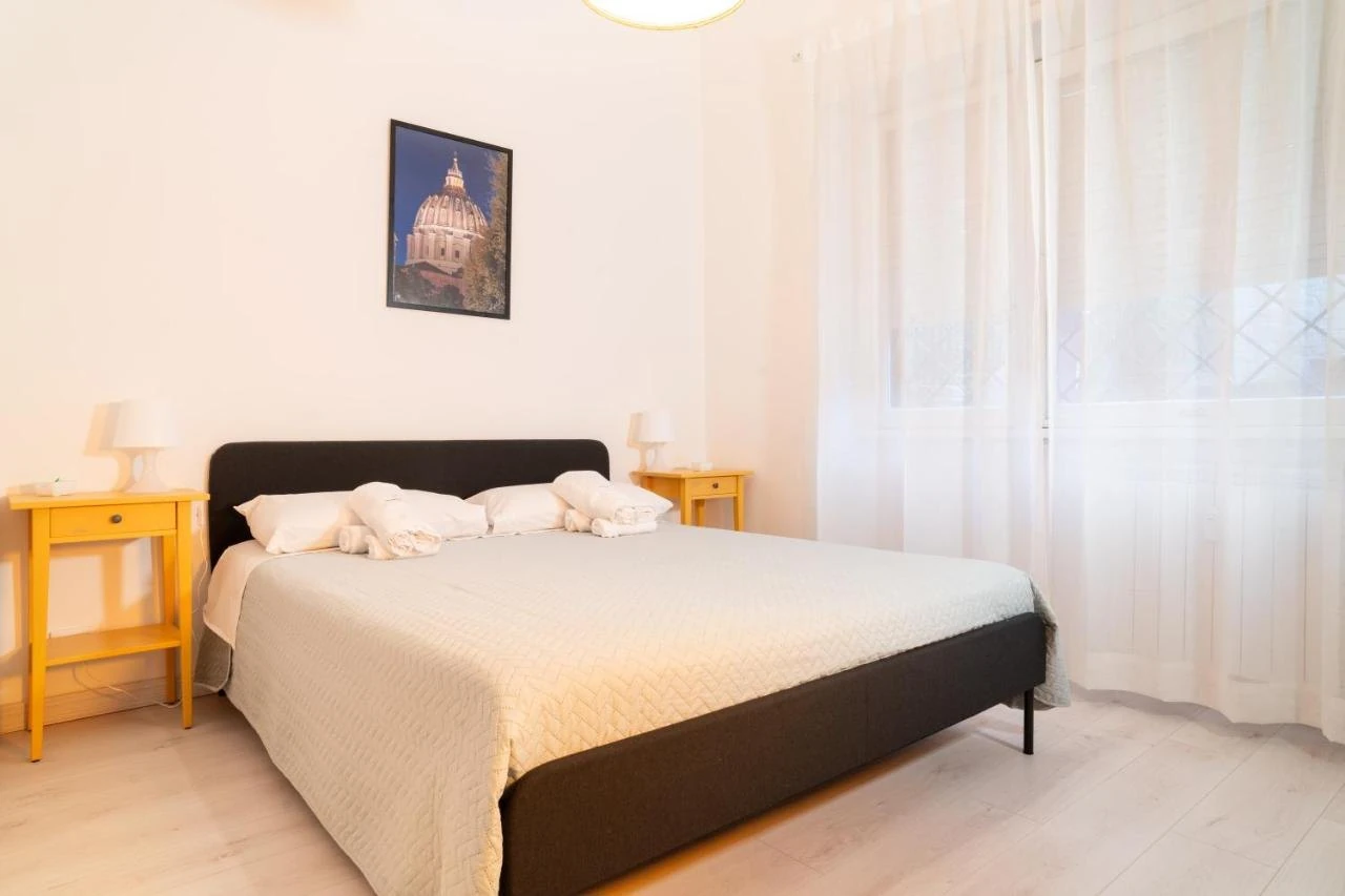 La camera da letto con i comodini gialli e la stampa della cupola di San Pietro